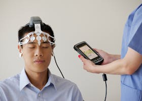Healthcare professional conducting an EEG examination using a Brainscope device on a male patient.