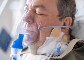 Close-up of a senior patient wearing an oxygen mask in a hospital setting.