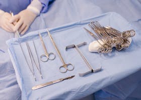 A set of surgical instruments carefully arranged on a blue drape during an operation.