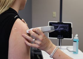 Healthcare professional conducting an ultrasound on a shoulder injury in a medical office.