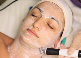 Client receiving advanced skincare treatment with facial toning device in a clinic.