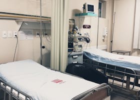 An empty hospital room equipped with two beds, monitoring equipment, and ambient lighting.
