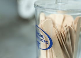 Close-up of wooden tongue depressors in a transparent jar, ideal for medical use.
