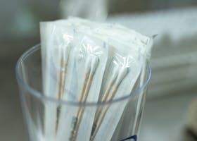Close-up of individually packaged sterile cotton swabs in a clear holder, ideal for medical use.