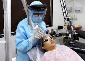 A medical practitioner performs laser treatment on a woman for skin care.