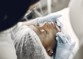 Close-up of a woman receiving a cosmetic lip injection in a clinic setting.