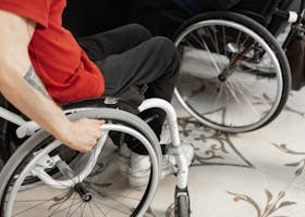 Close-up of person in wheelchair wearing red shirt, indoors.