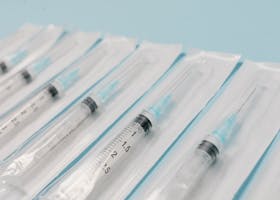 Close-up of sterile syringes aligned on a light blue surface, highlighting medical equipment.