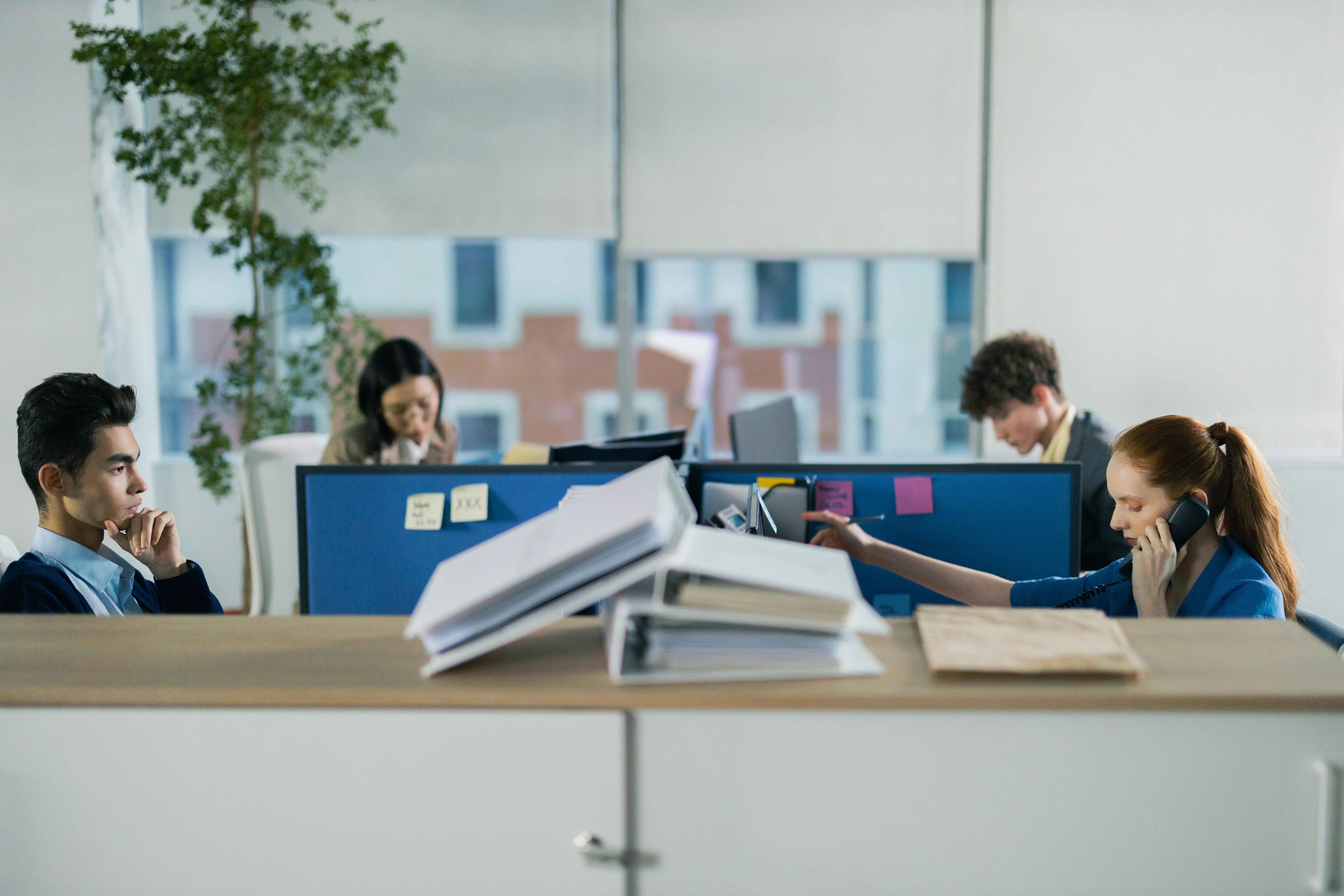 Contemporary office setting with diverse employees working diligently at their cubicles.
