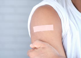 A close-up image of an adult with a bandage on the upper arm, likely after vaccination.