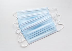 A stack of blue surgical face masks neatly arranged on a white background.